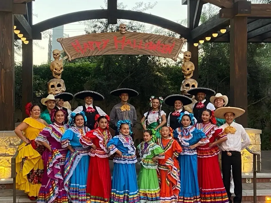 Ballet Folklórico Mi Herencia dancers on a Halloween-decorated stage at a theme park event