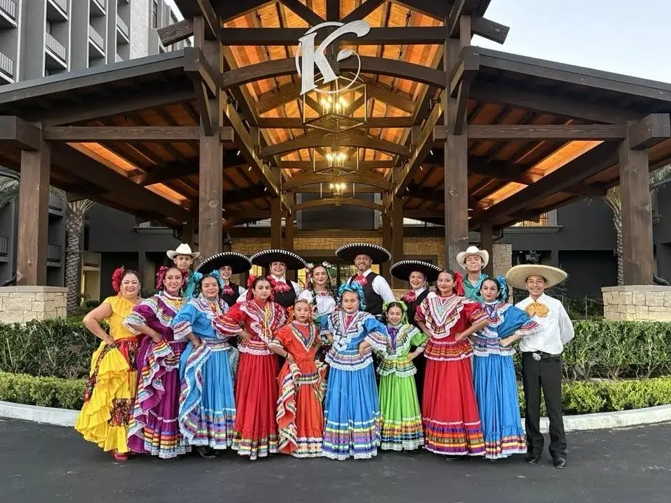 Ballet Folklórico Mi Herencia full group in Jalisco dresses and charro suits at a hotel entrance in Orange County