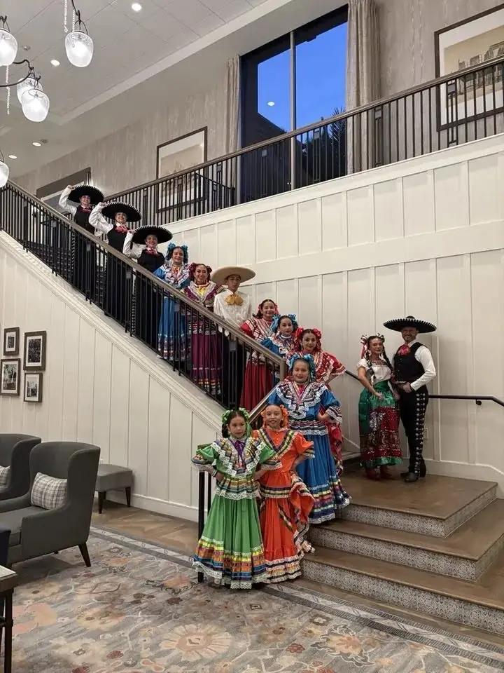 Ballet Folklórico Mi Herencia dancers posed along a hotel staircase in colorful folklorico dresses
